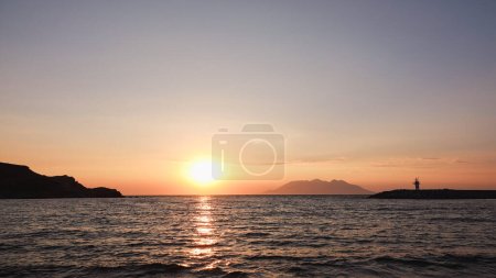 Téléchargez les photos : Vue sur le port maritime, le phare, les montagnes et l'île opposée de Samothrace à Gokceada, île d'Imbros au coucher du soleil - en image libre de droit