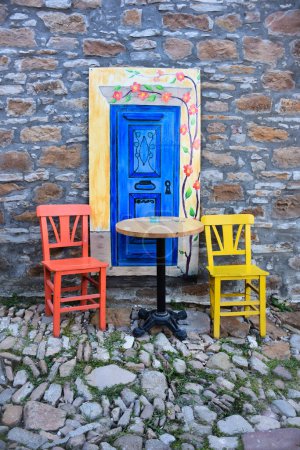 Téléchargez les photos : Décoration de porte extérieure colorée avec chaises colorées et table dans une vieille rue pavée. Zeytinlikoy (Aghios Theodoros), Gokceada (Imbros), Turquie. 22.08.2020 - en image libre de droit