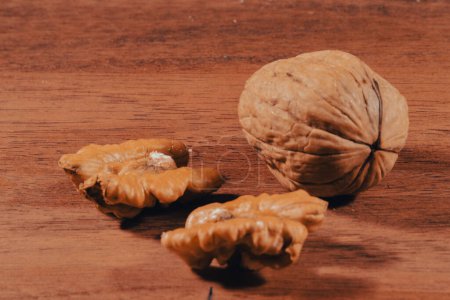 Photo for Heaps of walnuts, one of which has been opened, waiting to be eaten on a wooden table - Royalty Free Image