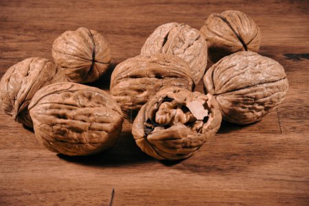 Photo for Heaps of walnuts, one of which has been opened, waiting to be eaten on a wooden table - Royalty Free Image