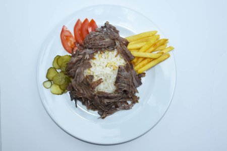 Foto de Top view of Iskender doner kebab with rice, fried potatoes, tomatoes and pickled cucumbers served on a white plate - Imagen libre de derechos