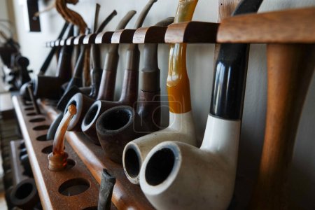 A collection of old briar pipes for smoking on a wooden stand. Old tobacco pipes.