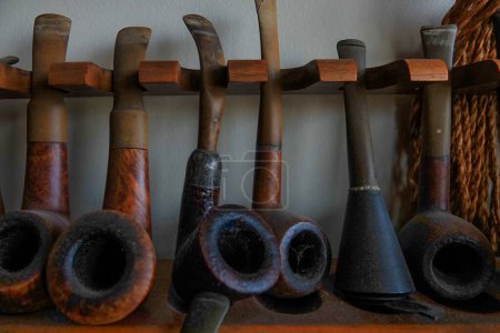 A collection of old briar pipes for smoking on a wooden stand. Old tobacco pipes.