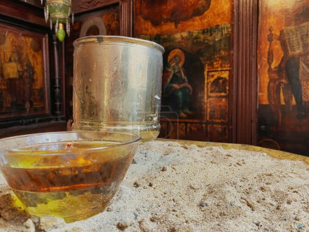 Photo for Wishing  candle in a glass on an iron table in an old orthodox chapel with religious icons - Royalty Free Image