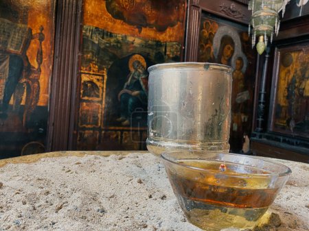 Photo for Wishing  candle in a glass on an iron table in an old orthodox chapel with religious icons - Royalty Free Image