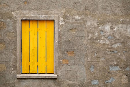 Foto de Fachada de una antigua casa de piedra con ventanas con persianas amarillas - Imagen libre de derechos