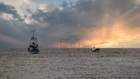 Téléchargez les photos : Un petit bateau de pêche et un bateau d'espadon revenant de la mer à Gkeada - en image libre de droit