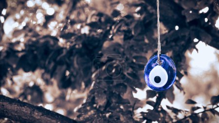 Foto de Perla azul del mal de ojo colgando con una cuerda de una rama de árbol. Amuleto tradicional del mal de ojo. Un símbolo nacional y guardián en Turquía. - Imagen libre de derechos