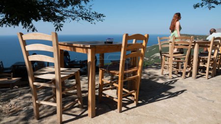 Photo for Gokceada (Imbros) coastline and a cute village tea garden view with wooden chairs and table. Tepeky village, naralt-Pinarbasi location, Aegean Turkey - Royalty Free Image