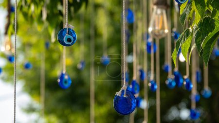 Foto de Perlas azules del mal de ojo colgando con una cuerda de una rama de árbol. Amuleto tradicional del mal de ojo. Un símbolo nacional y guardián en Turquía. - Imagen libre de derechos