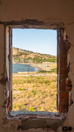 Téléchargez les photos : Fenêtre donnant sur la mer dans une maison abandonnée en face de la ville maritime de Kalekoy. La mer Égée vue sur la ville depuis la fenêtre. Gokceada, île d'Imbros, Canakkale. - en image libre de droit