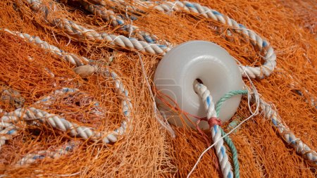 Close-up of orange tangled fishing net and buoys  on the quayside