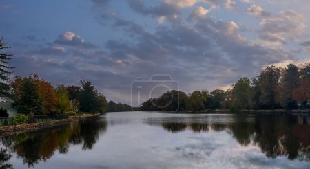 Photo for View of the Brainerd Lake in autumn in Cranbury, New Jersey, United States. Autumn landscape with lake, trees and cloudy sky reflected in water - Royalty Free Image