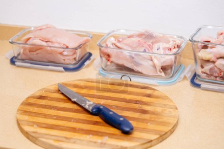 Préparation d'un poulet à couper et à conserver dans des contenants.