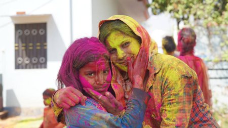 Foto de Imagen al aire libre de Asia, India feliz madre hija en vestido indio celebrando el festival Holi junto con polvo de color. - Imagen libre de derechos