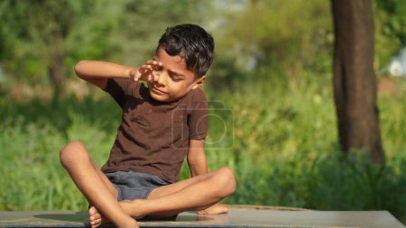 Photo for Child practicing yoga in the park in day time. Boy is doing yoga in clean and green environment and fresh air. - Royalty Free Image