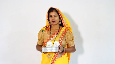 Woman happily posing while holding a festival Puja thali. Female looking towards the camera with a smile on her face - Diwali Karwa Chauth festival