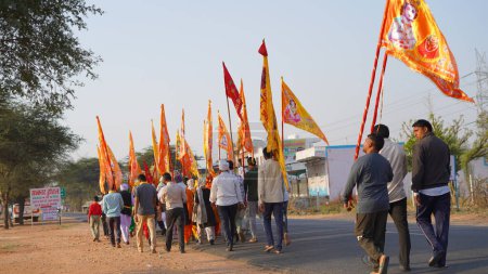 Photo for 15 November 2023 Jaipur, Rajasthan, India. Pilgrims or warkari with saffron flags during khatushyamji yatra on the road. - Royalty Free Image