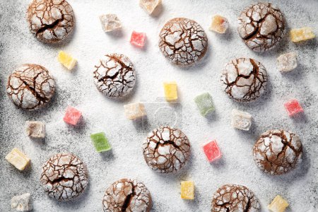 Photo for Top down view of many scattered crackled cocoa cookies and colorful turkish delight slices over snow like powdered sugar background. Traditional Christmas treats viewed from above. - Royalty Free Image
