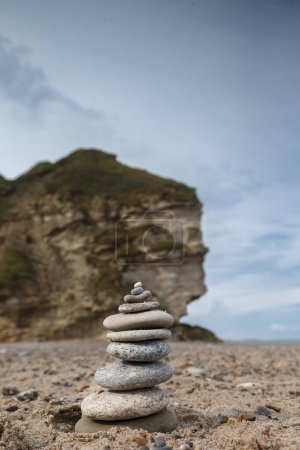 Foto de Una hermosa toma de una roca en una playa de arena bajo el cielo azul - Imagen libre de derechos