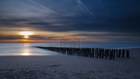 Sonnenuntergang an der Küste von Vlissingen Holland mit den Holzpfählen
