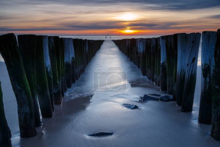 Puesta de sol en la costa de Vlissingen Holanda con los postes de madera