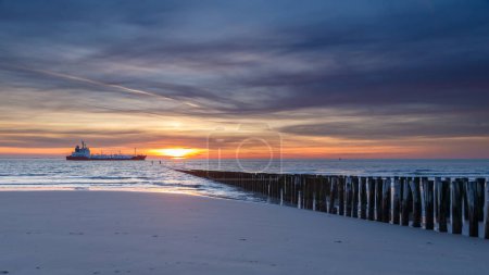 Puesta de sol en la costa de Vlissingen Holanda con los postes de madera