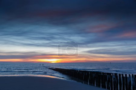 Sunset at the coast of Vlissingen Holland with the wooden poles