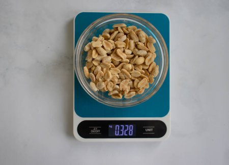 Foto de Electronic kitchen scales, peanuts on a light background - Imagen libre de derechos