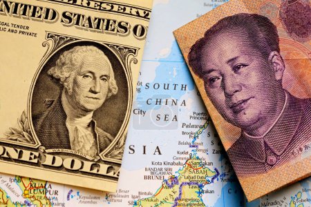 Close-up of a US dollar bill and a yuan Chinese banknote on top of a map showing the South China Sea