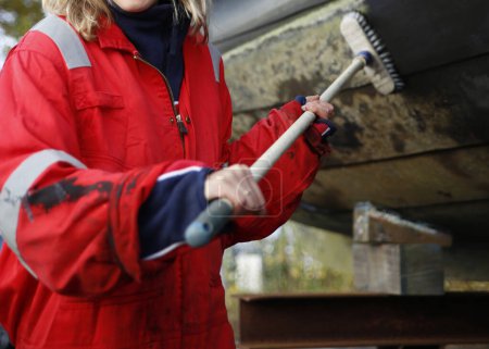 Photo for Close-up of a young woman cleaning her boat in a marina, Holland - Royalty Free Image
