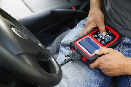 Foto de Un mecánico de automóvil inspeccionando un automóvil usando un dispositivo de diagnóstico electrónico - Imagen libre de derechos