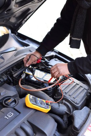 Téléchargez les photos : Un mécanicien automobile inspectant une voiture à l'aide d'un dispositif de diagnostic électronique - en image libre de droit