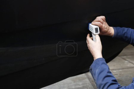 Téléchargez les photos : Ingénieur de service mesurant l'épaisseur de la coque en acier d'un bateau à l'aide d'un appareil à ultrasons - en image libre de droit
