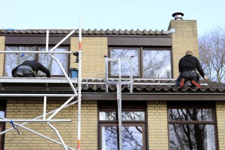 Photo for Service engineers installing solar panels on a roof of a residential house - Royalty Free Image