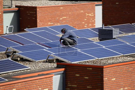 Téléchargez les photos : Ingénieurs de service installant des panneaux solaires sur le toit d'une maison résidentielle - en image libre de droit