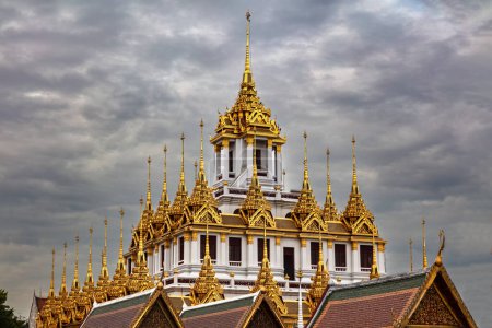 Foto de Templo de metal (Wat Ratchanatdaram) en Bangkok, Tailandia. Espiras de metal en el techo. Cielo nublado oscuro sobre la cabeza - Imagen libre de derechos