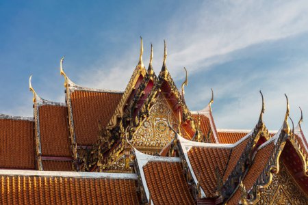 Decorative rooftop in red tile and golden trim, at the Marble Temple (Wat Benchamabophit Dusitvanaram), Bangkok, Thailand.