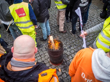 Foto de Berlín, Alemania - 06 de marzo de 2023: Huelga de advertencia frente a las puertas de la empresa de limpieza de la ciudad de Berliner con humo naranja y banderas ondeantes del sindicato Verdi. - Imagen libre de derechos