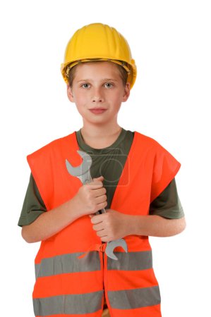 Téléchargez les photos : Vue du haut du corps avant d'un garçon de 10 ans portant un gilet de sécurité orange et tenant une grande clé à bout ouvert devant lui isolé sur blanc. - en image libre de droit