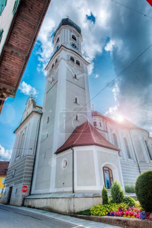 Photo for Nesselwang, Germany - July 06, 2023: Extreme wide angle view of the Saint Andreas Church with bell tower in Nesselwang from the north against a cloudy sky. - Royalty Free Image