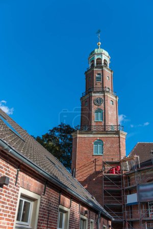 Foto de Campanario de la gran iglesia reformada con andamios para trabajos de mantenimiento en Frisia Oriental en otoño de 2022 en clima soleado con cielo azul. - Imagen libre de derechos