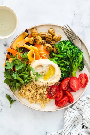 Téléchargez les photos : Salade de quinoa équilibrée avec brocoli, houmous, tomates, olives, carottes et persil, vue sur le dessus. Concept alimentaire végétalien de désintoxication, bol de bouddha. - en image libre de droit