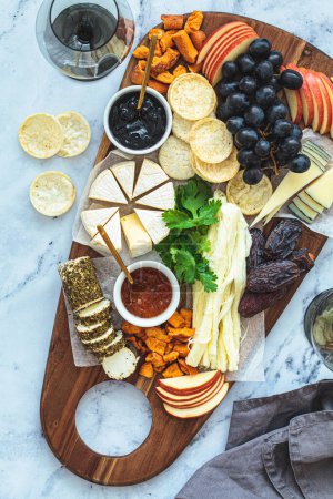 Cheese board with fruits and crackers, top view. Party food, food platter, european appetizers.
