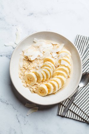 Photo for Overnight vegan oatmeal with banana and coconut chips, top view. - Royalty Free Image