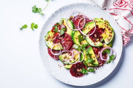 Blood oranges salad with avocado, pistachios and red onions, top view, white background.