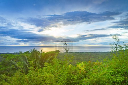 Sunset over a lush tropical landscape with ocean views, where rays break through the cloud cover. High quality photo. Uvita Puntarenas Province Costa Rica.