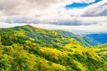 Grüne Hänge von Monteverde unter einem dynamischen Himmel, die die reiche Artenvielfalt und die vielschichtigen Ausblicke auf die Berge der Provinz Puntarenas, Costa Rica, präsentieren. Hochwertiges Foto