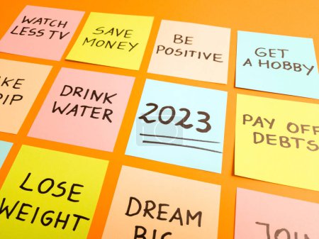 Foto de Resoluciones de Año Nuevo 2023 escritas a mano sobre notas adhesivas de colores sobre fondo naranja. Planificación futura, motivación, cambio, desafío y concepto de mejora personal - Imagen libre de derechos