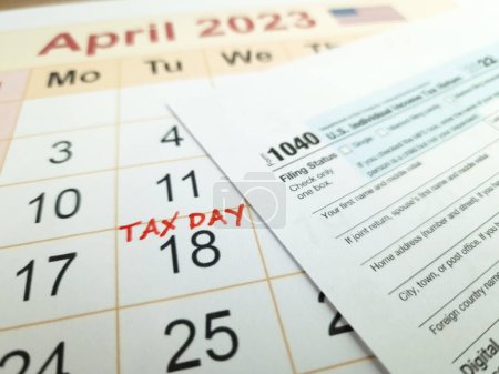 Téléchargez les photos : Tax payment day marked on a calendar - April 18, 2023 with 1040 form, financial concept - en image libre de droit